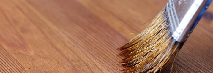 Pinsel trägt Lasur auf Holz auf